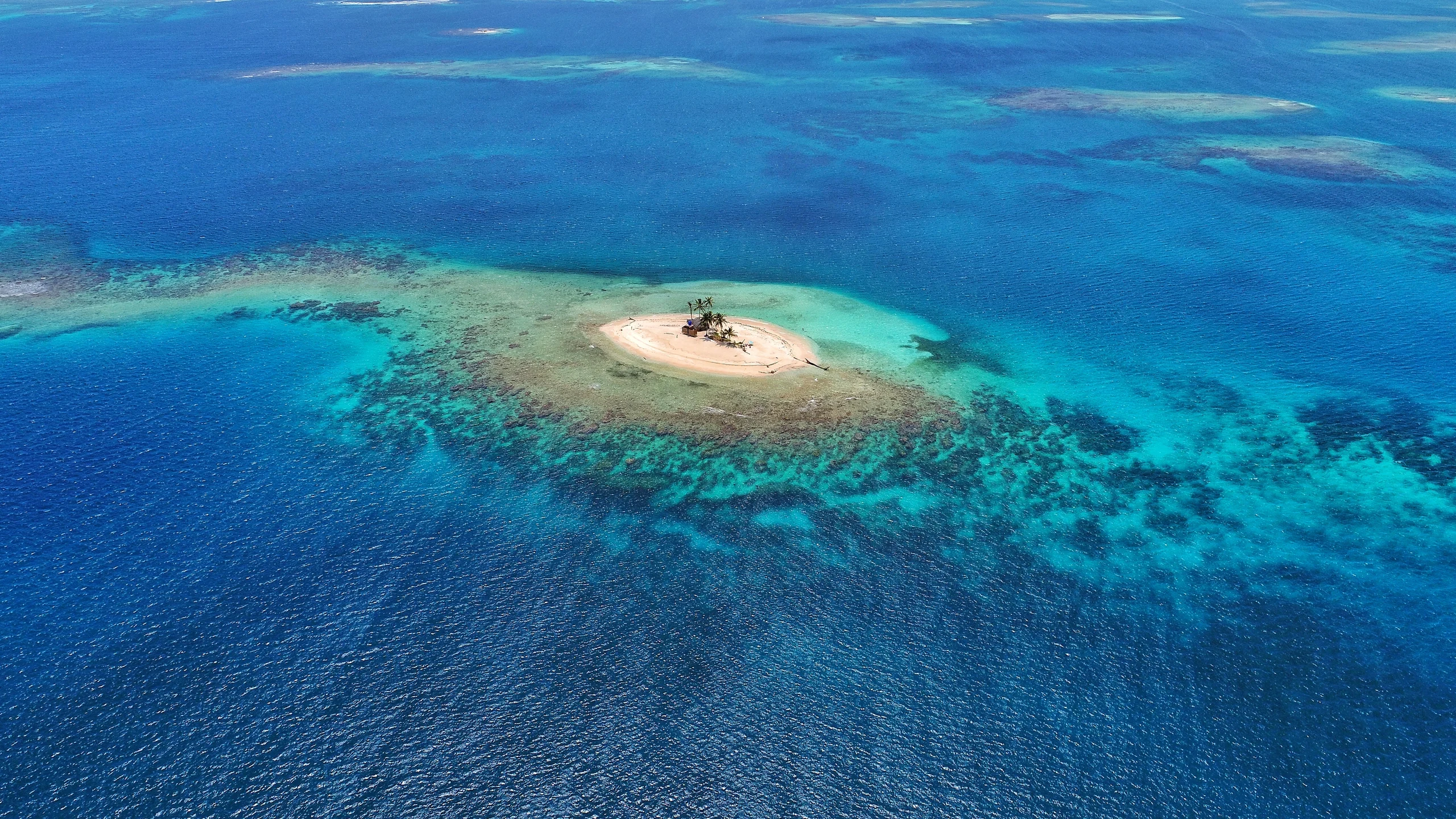 Aerial view of the San Blas Islands, Panama, showcasing turquoise waters, white sandy beaches, and lush green palm trees.