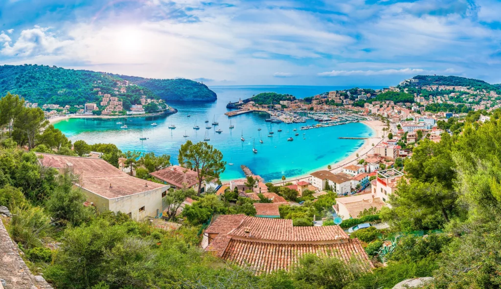 Luxury yacht anchored in a serene bay in Mallorca, Spain, with turquoise waters, golden sandy beaches, and lush green hills in the background