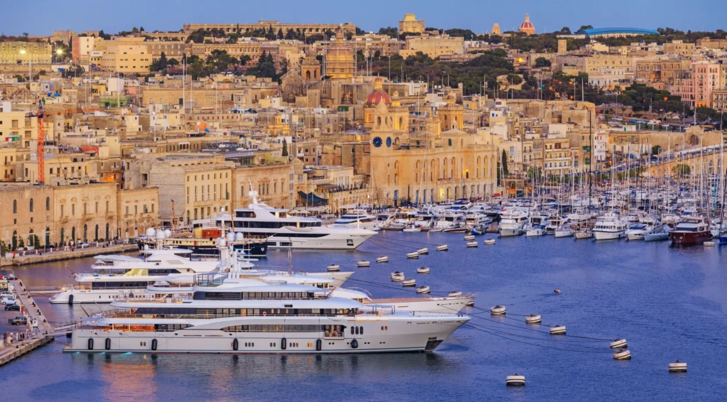Luxury yacht anchored in Valletta Marina, Malta, with the iconic St. John’s Co-Cathedral, historic waterfront, and turquoise waters in the background