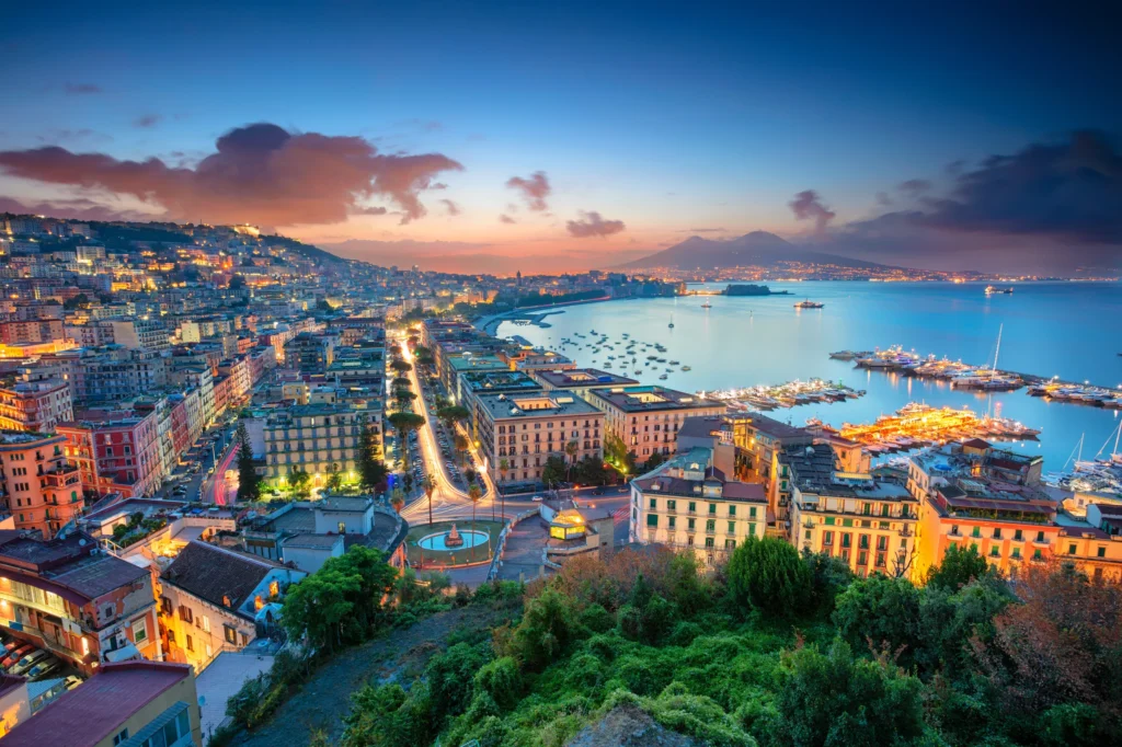 Luxury yacht anchored near the coastline of Naples, Italy, with Mount Vesuvius, turquoise waters, and the vibrant cityscape in the background
