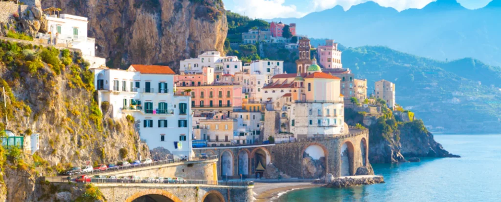 Luxury yacht cruising along the Amalfi Coast, Italy, with iconic cliffs, turquoise waters, charming coastal towns, and Capri in the background