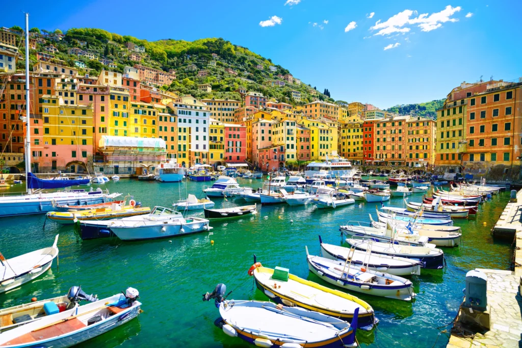 Luxury yacht anchored near Portofino, Italian Riviera, with colorful cliffside houses, sparkling blue waters, and lush coastal landscapes.
