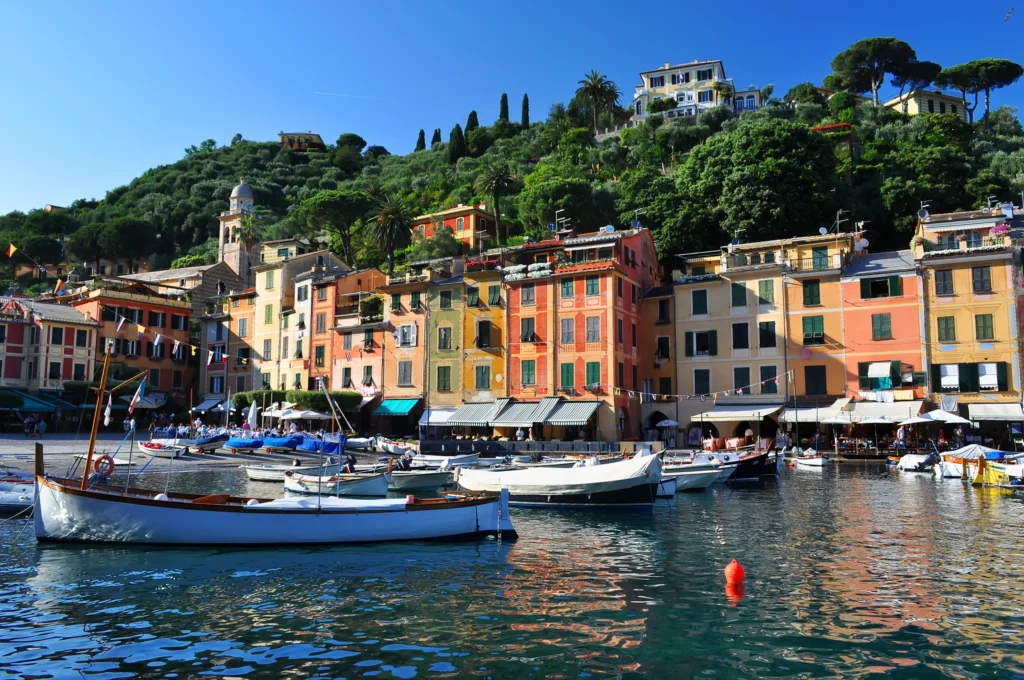 Luxury yacht anchored near Portofino, Italian Riviera, with colorful cliffside houses, sparkling blue waters, and lush coastal landscapes.