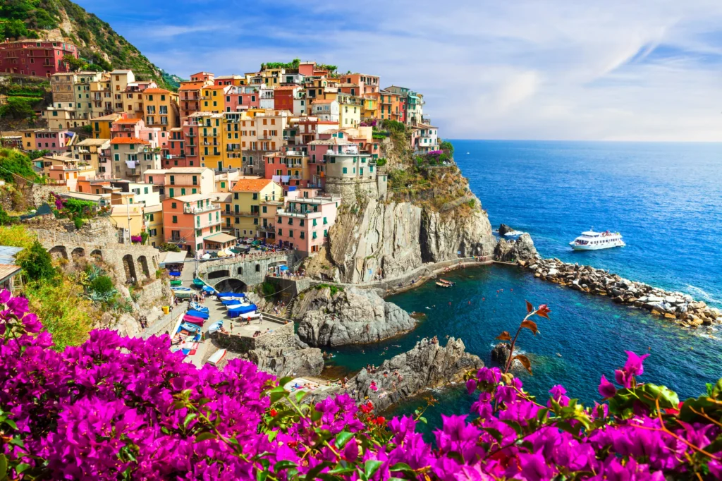 Luxury yacht anchored near the Cinque Terre coastline, Italy, with colorful cliffside villages, terraced vineyards, and turquoise waters in the background