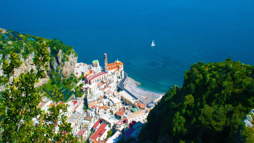Luxury yacht anchored near the coastline of Salerno, Italy, with the iconic waterfront, turquoise waters, and lush green hills in the background