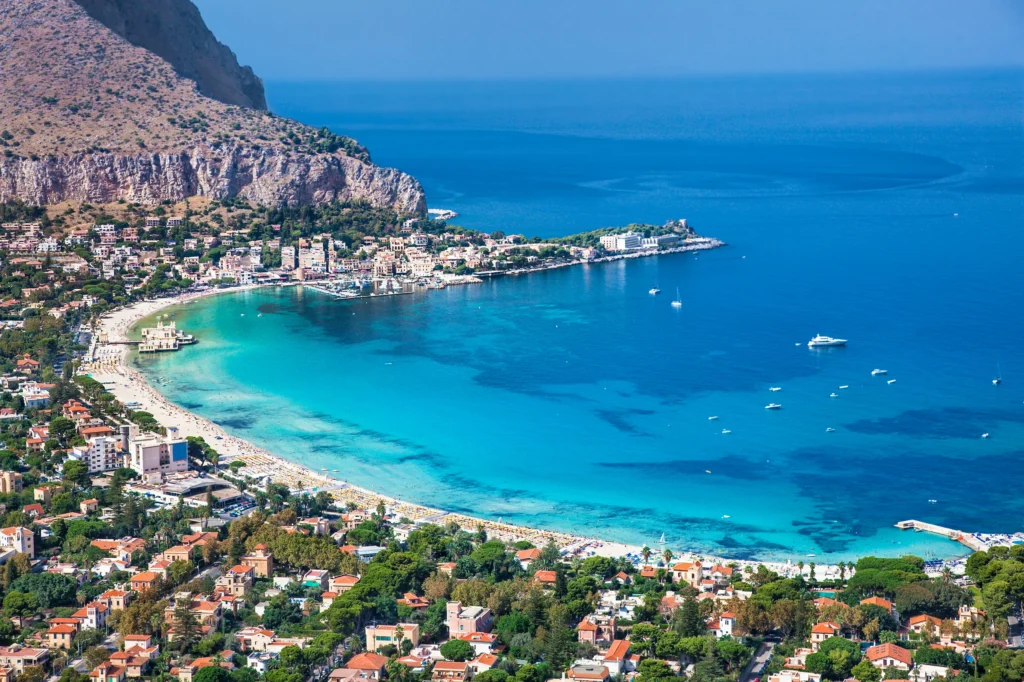 Luxury yacht anchored near Palermo Harbor, Sicily, Italy, with the historic skyline, turquoise waters, and vibrant cityscape in the background