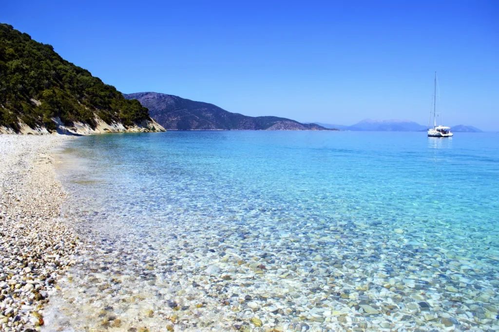 Luxury yacht cruising near Ithaca, Greece, with pristine Ionian Sea waters, rugged coastlines, and lush island scenery.