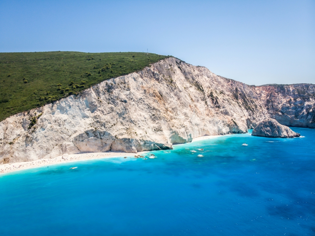 Luxury yacht cruising near Lefkada with sparkling Ionian Sea waters, scenic coastal cliffs, and views of Corfu in the distance.