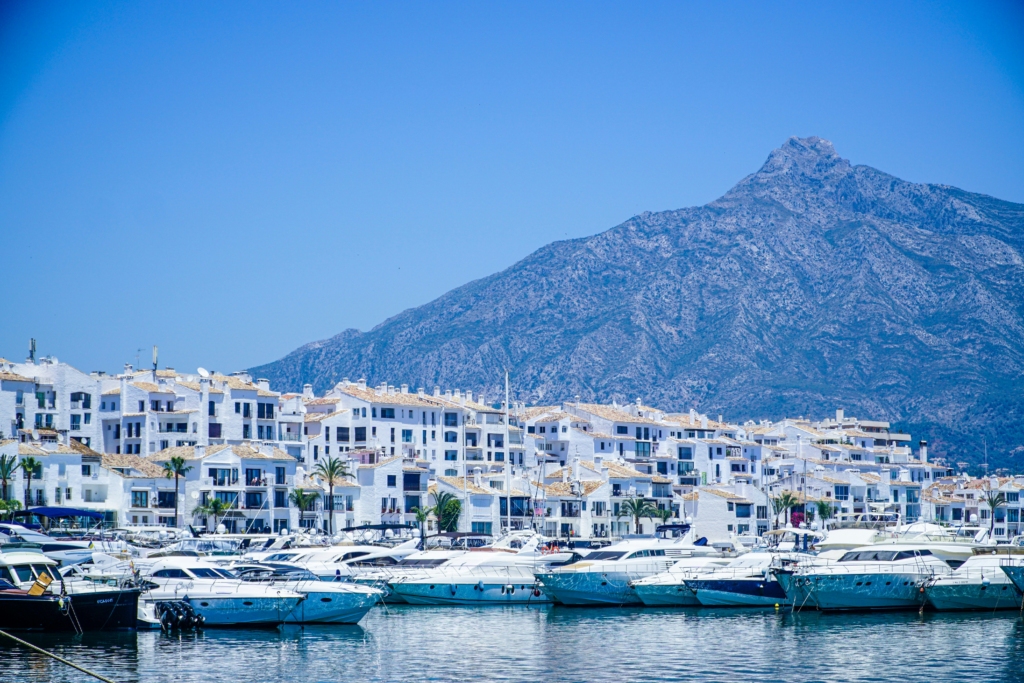 Luxury yacht cruising near Marbella, Spain, with turquoise Mediterranean waters, a vibrant marina, and scenic coastal views