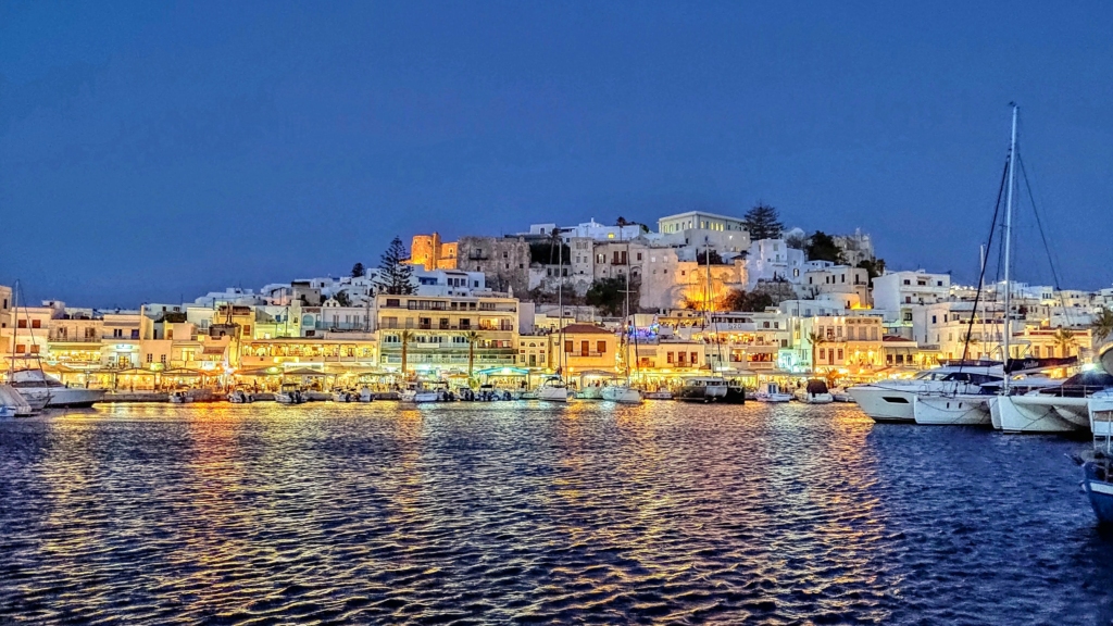Luxury yacht cruising near Naxos in the Cyclades Islands, Greece, with pristine blue waters, charming coastal landscapes, and ancient ruins in the background
