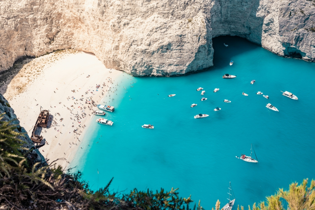 Luxury yacht cruising near Zakynthos with vibrant Ionian Sea waters, dramatic cliffs, and lush island scenery with hints of Corfu in the distance.