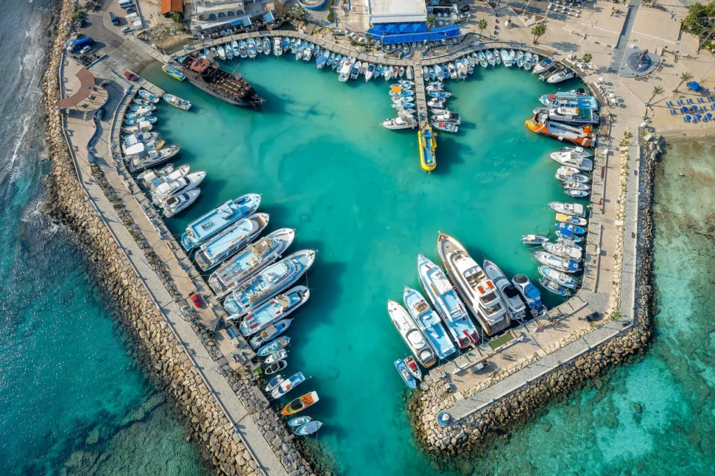 Luxury yacht cruising near Ayia Napa, Cyprus, with clear Mediterranean waters, lively coastal scenes, and scenic harbor views.