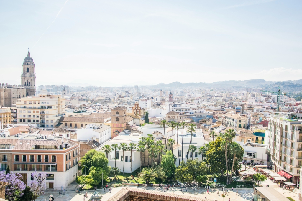 Luxury yacht cruising off Malaga's coast, Spain, with clear Mediterranean waters, a historic port, and a vibrant marina backdrop