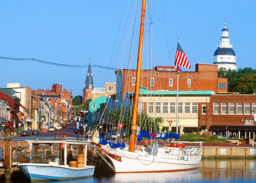 Luxury yacht sailing in the Chesapeake Bay near Annapolis, Maryland, with the historic skyline, sailboats, and calm blue waters in the background