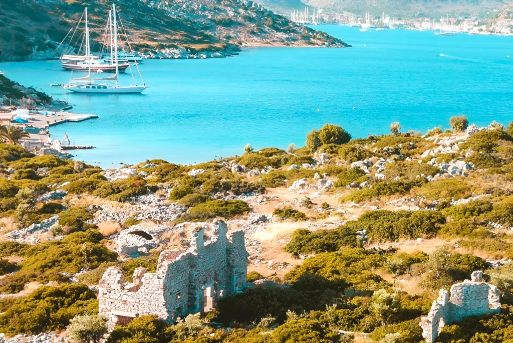 Luxury yacht cruising near Bodrum, Turkey, with pristine turquoise waters, scenic coastal views, and a vibrant marina backdrop.