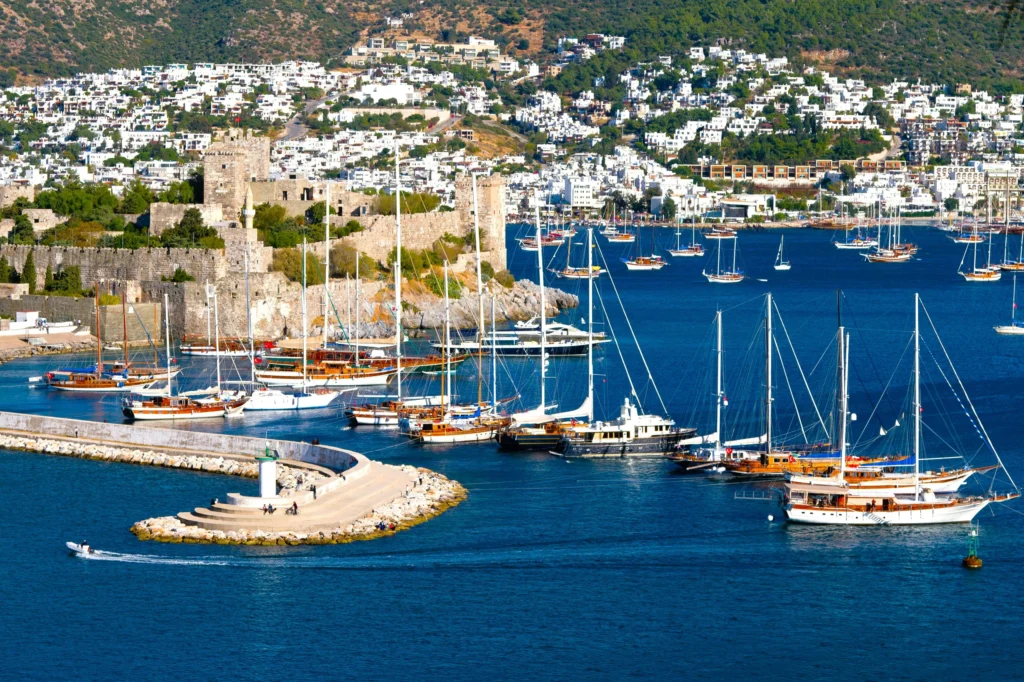 Luxury yacht cruising near Bodrum, Turkey, with pristine turquoise waters, scenic coastal views, and a vibrant marina backdrop.
