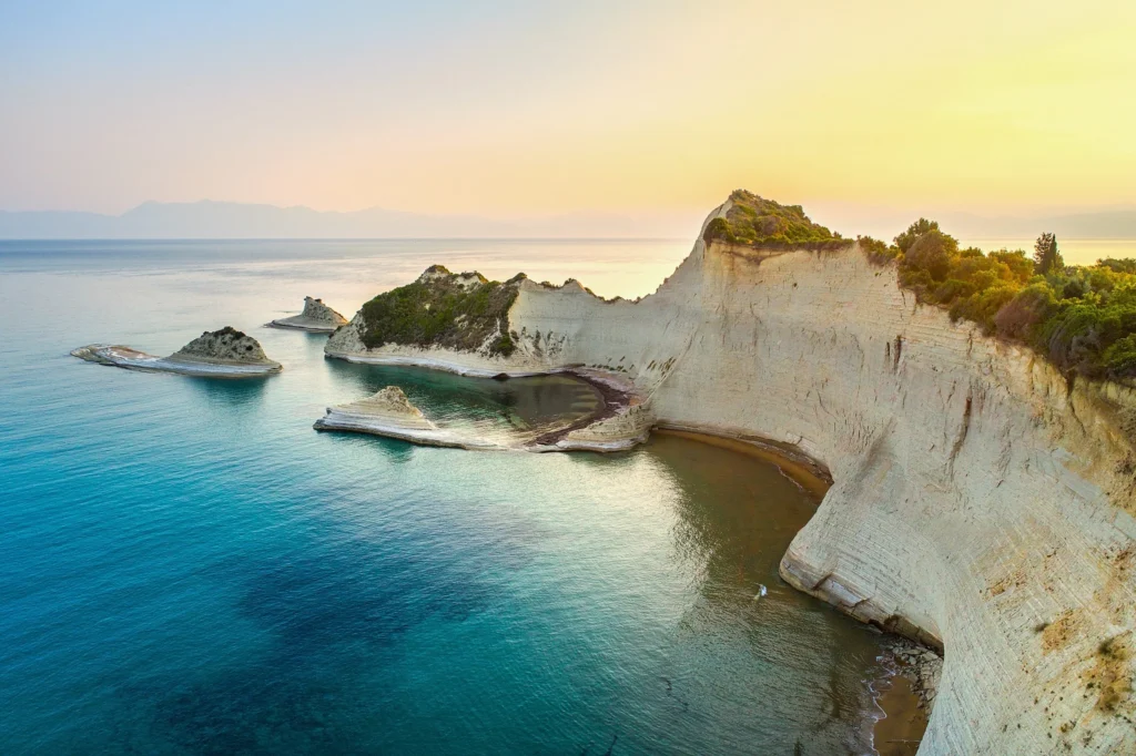 Luxury yacht cruising near Corfu with clear Ionian Sea waters, lush greenery, and picturesque coastal scenery in Greece.