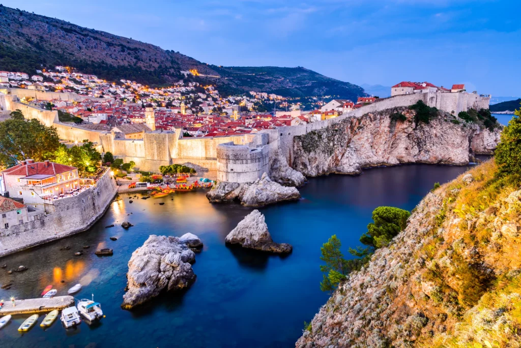 Luxury yacht cruising along Dubrovnik's ancient coastline in Croatia, with crystal-clear Adriatic waters and historic city walls in view.