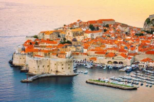 Luxury yacht cruising along Dubrovnik's ancient coastline in Croatia, with crystal-clear Adriatic waters and historic city walls in view.
