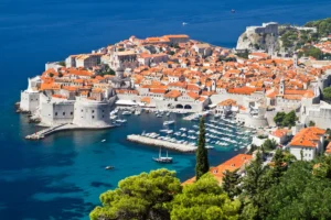 Luxury yacht cruising along Dubrovnik's ancient coastline in Croatia, with crystal-clear Adriatic waters and historic city walls in view.