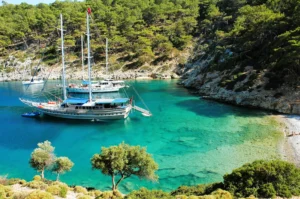 Luxury yacht cruising near Fethiye, Turkey, with crystal-clear turquoise waters, rugged coastline, and a charming marina.