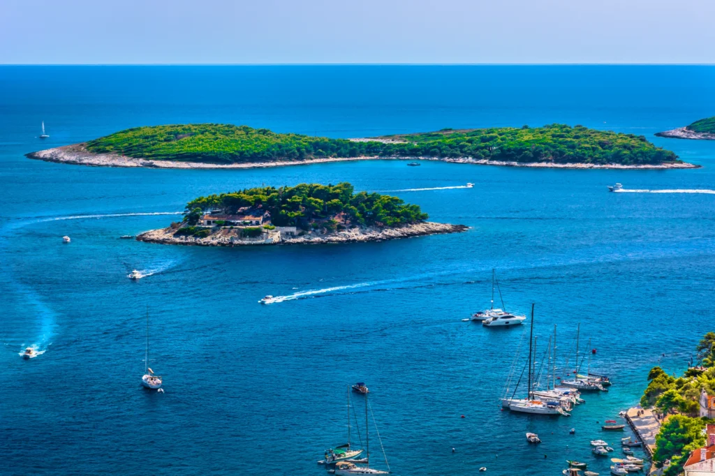 Luxury yacht cruising near Hvar, Croatia, with sparkling Adriatic waters, charming coastal views, and a vibrant port atmosphere.