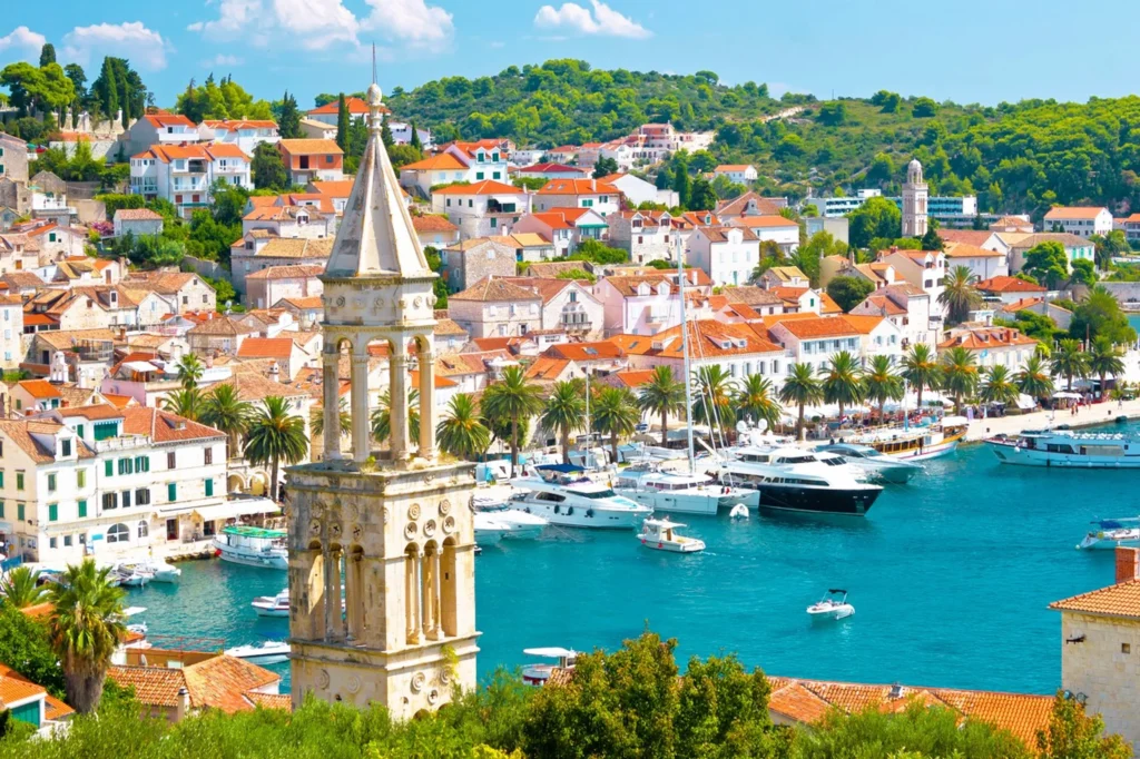 Luxury yacht cruising near Hvar, Croatia, with sparkling Adriatic waters, charming coastal views, and a vibrant port atmosphere.