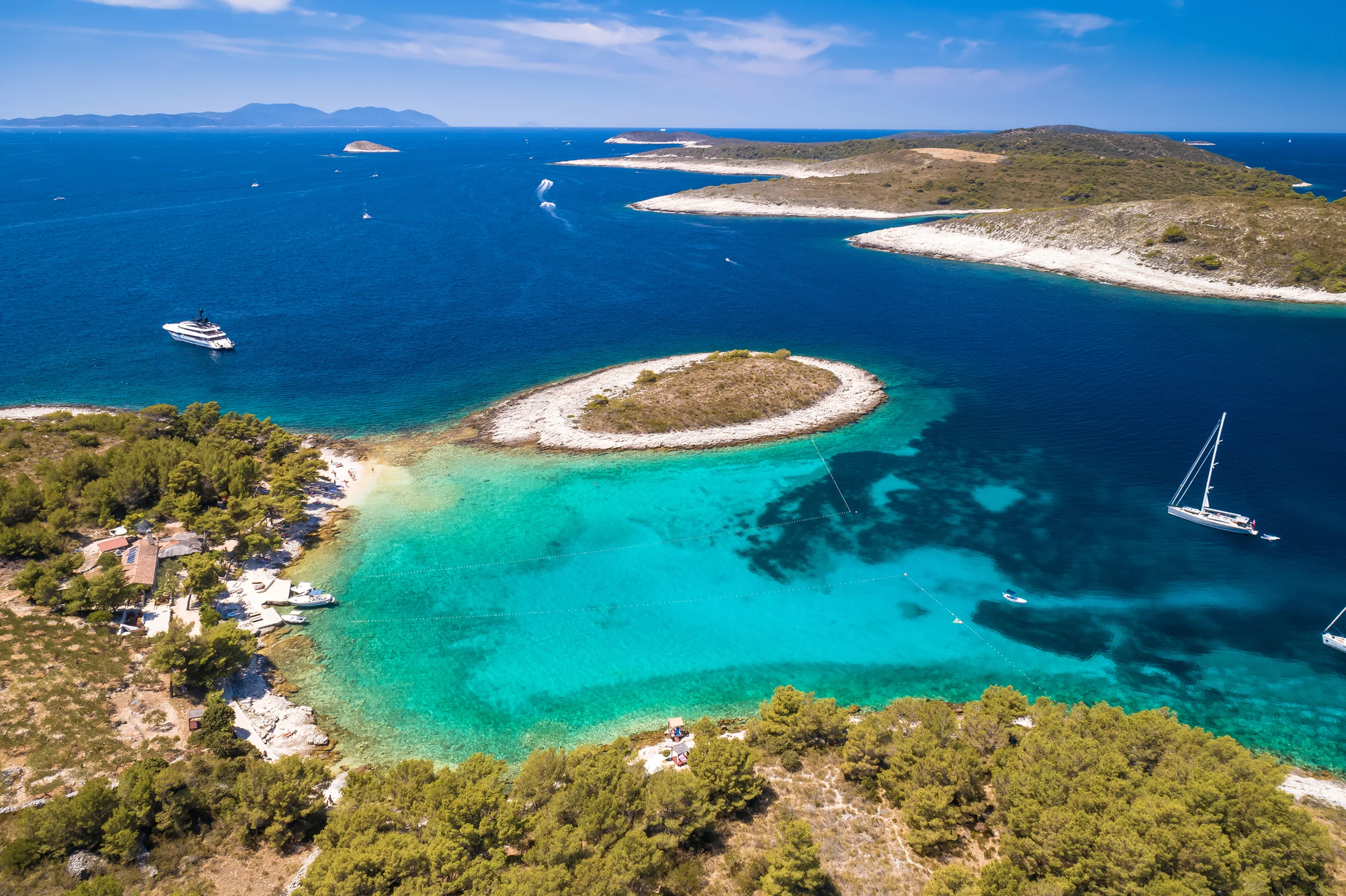 Luxury yacht cruising near Hvar, Croatia, with sparkling Adriatic waters, charming coastal views, and a vibrant port atmosphere.