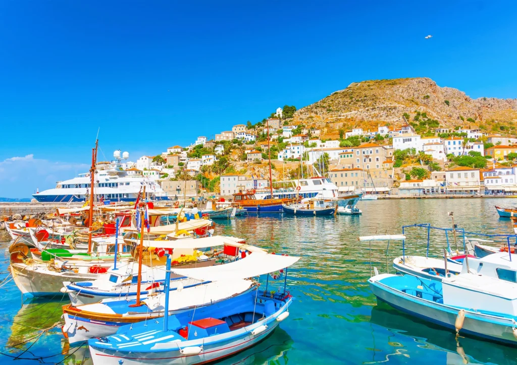Luxury yacht cruising near Hydra, Greece, with charming stone buildings, crystal-clear Saronic Gulf waters, and a scenic harbor