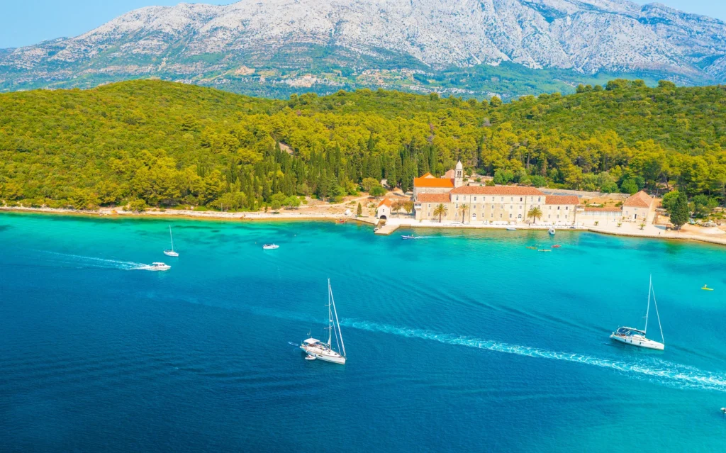 Luxury yacht cruising near Korčula, Croatia, with turquoise Adriatic waters, historic coastal charm, and scenic island vistas.