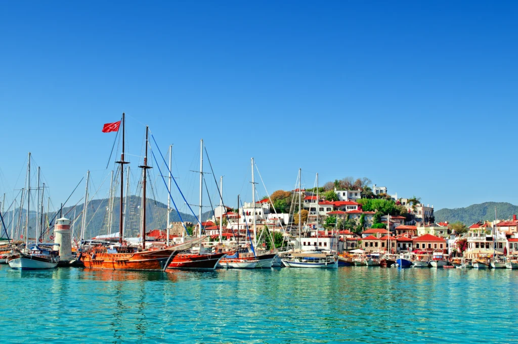 Luxury yacht cruising near Marmaris, Turkey, with sparkling turquoise waters, rugged coastline, and a vibrant marina.