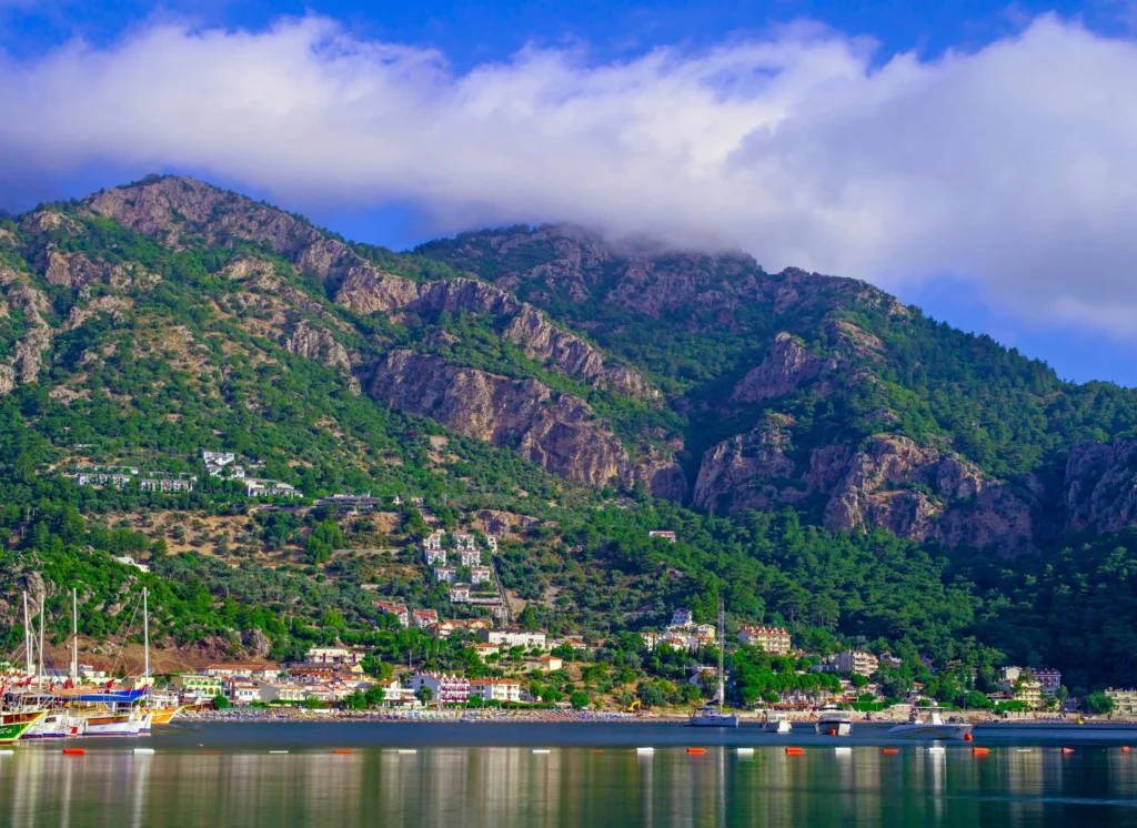Luxury yacht cruising near Marmaris, Turkey, with sparkling turquoise waters, rugged coastline, and a vibrant marina.