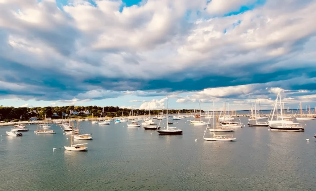 Luxury yacht anchored in Martha’s Vineyard Harbor, Massachusetts, with classic sailboats, a charming New England coastline, and vibrant waterfront activity