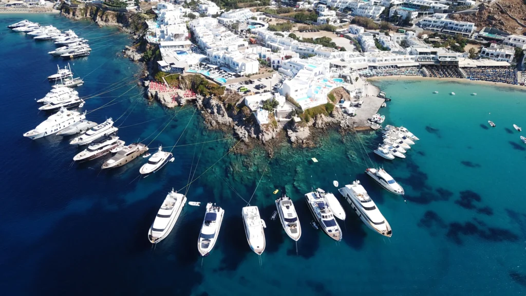 Luxury yacht cruising near Mykonos in the Cyclades Islands, Greece, with turquoise waters, iconic windmills, and vibrant coastal scenery