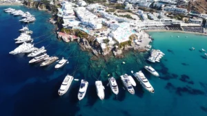 Luxury yacht cruising near Mykonos in the Cyclades Islands, Greece, with turquoise waters, iconic windmills, and vibrant coastal scenery