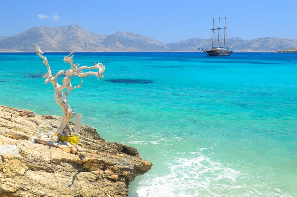 Luxury yacht cruising near Naxos in the Cyclades Islands, Greece, with pristine blue waters, charming coastal landscapes, and ancient ruins in the background