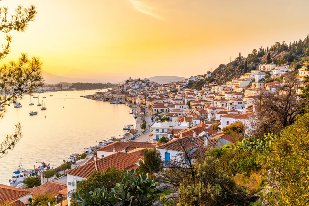 Luxury yacht cruising near Poros in the Saronic Gulf, Greece, with serene blue waters, lush landscapes, and a charming harbor