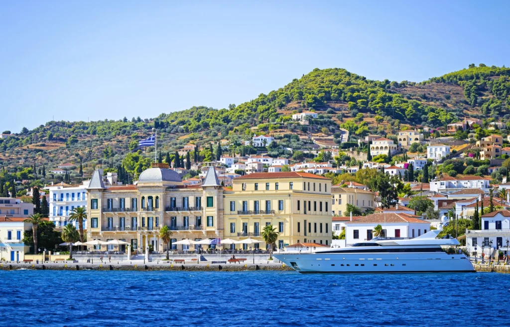 Luxury yacht cruising near Spetses in the Saronic Gulf, Greece, with scenic blue waters, charming architecture, and picturesque coastal views