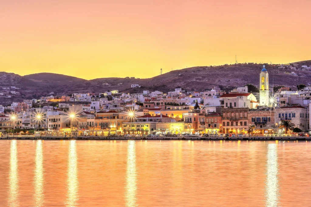 Luxury yacht cruising near Syros in the Cyclades Islands, Greece, with sparkling blue waters, charming neoclassical architecture, and scenic coastal views.