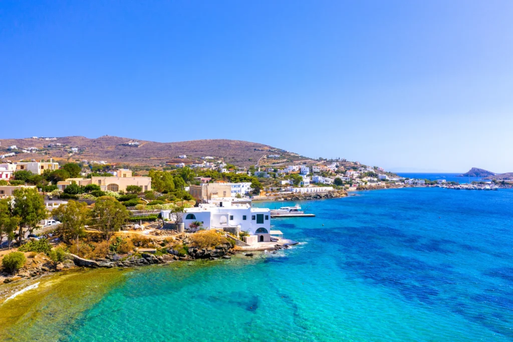 Luxury yacht cruising near Syros in the Cyclades Islands, Greece, with sparkling blue waters, charming neoclassical architecture, and scenic coastal views.