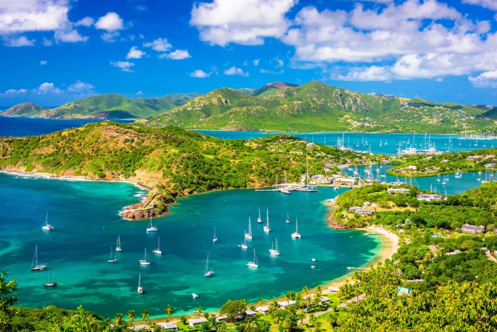 Luxury yacht cruising near Antigua in the Caribbean, featuring crystal-clear blue waters, lush tropical islands, and vibrant coastal scenery.