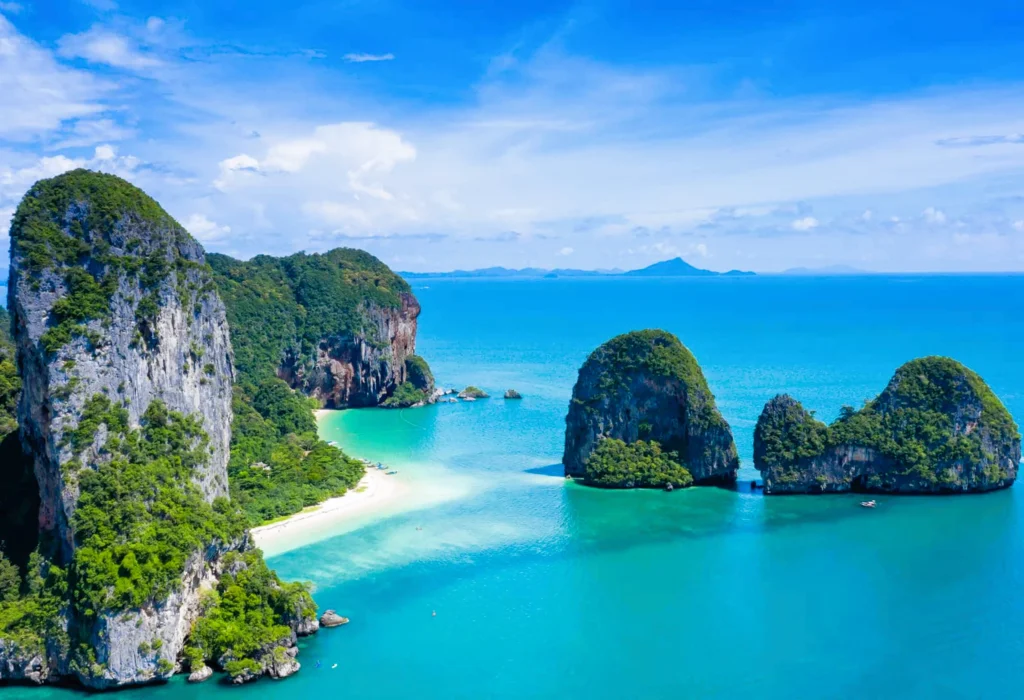 Luxury yacht cruising near Ao Nang, Thailand, with crystal-clear waters, dramatic limestone cliffs, and a vibrant coastal setting.
