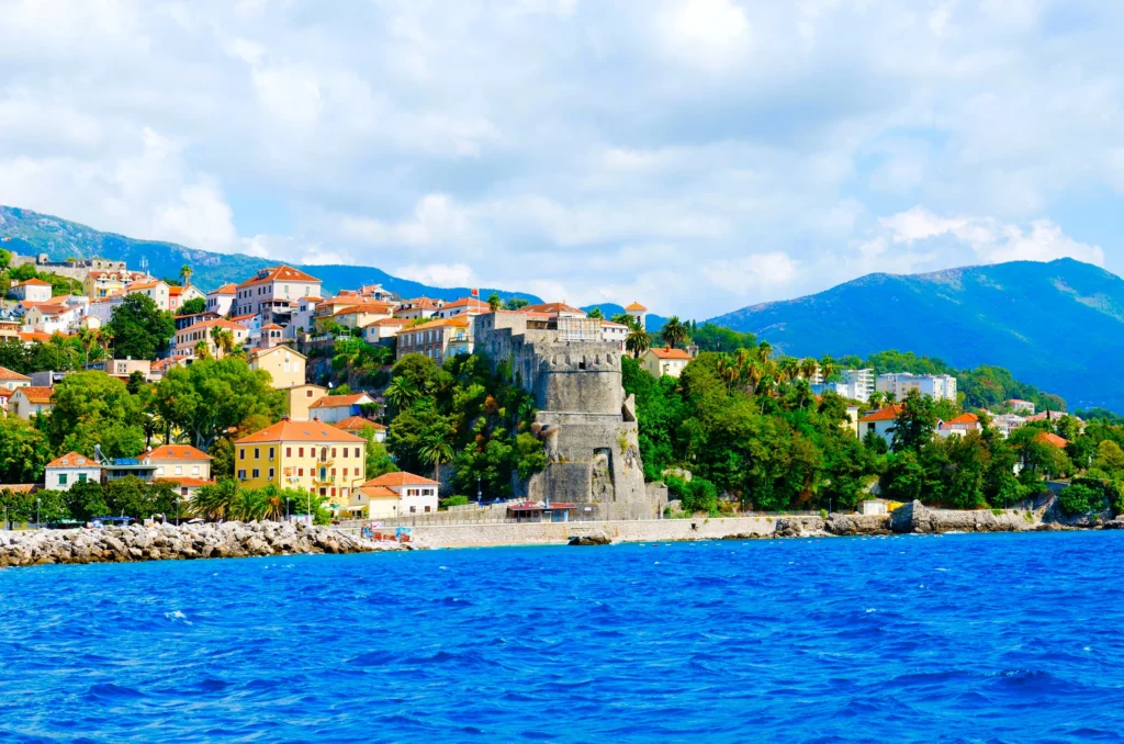 Luxury yacht cruising near Herceg Novi, Montenegro, with clear Adriatic waters, scenic harbor views, and historic coastal architecture.