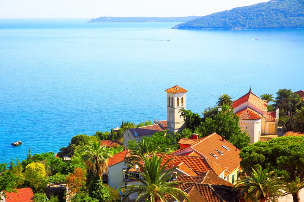 Luxury yacht cruising near Herceg Novi, Montenegro, with clear Adriatic waters, scenic harbor views, and historic coastal architecture.