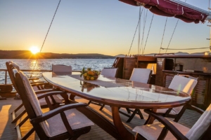 Traditional gulet yacht sailing on crystal-clear Mediterranean waters, with scenic coastlines of Greece, Turkey, Croatia, and Sicily in the background.