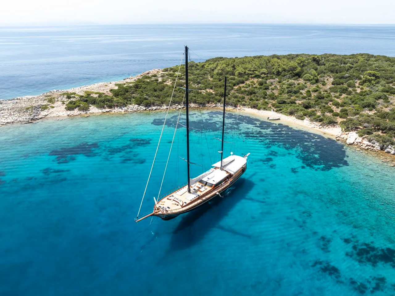 Traditional gulet yacht sailing on crystal-clear Mediterranean waters, with scenic coastlines of Greece, Turkey, Croatia, and Sicily in the background.