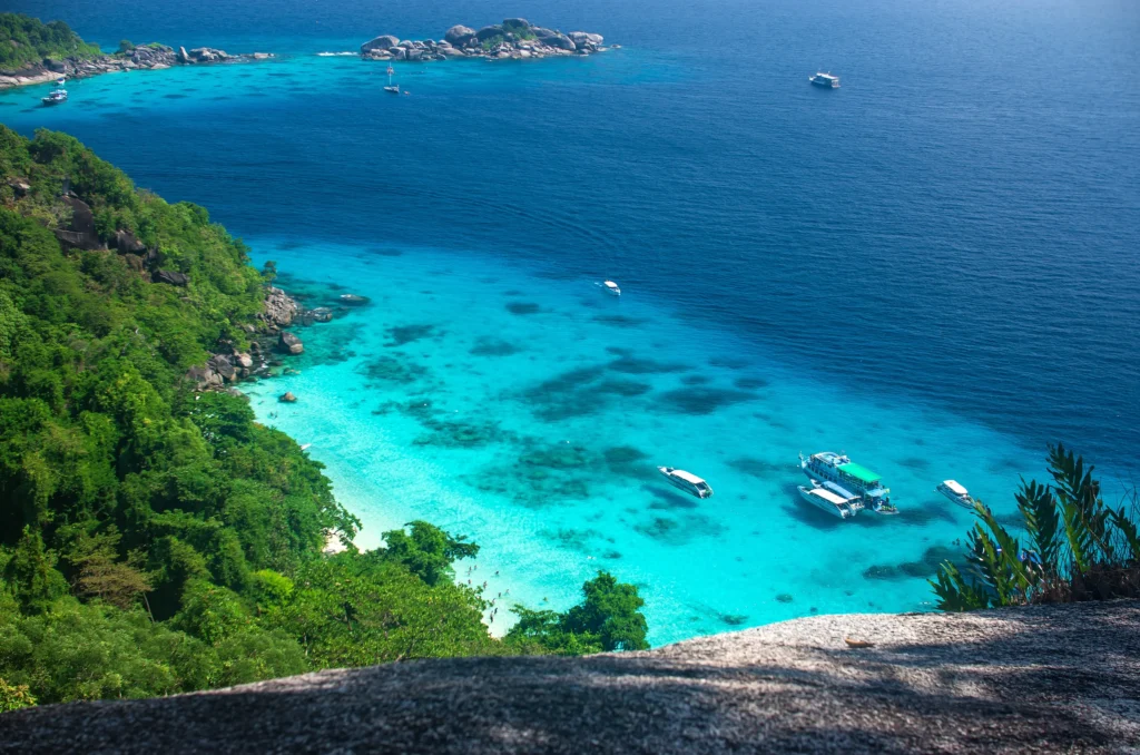 Luxury yacht cruising near the Similan and Surin Islands in Thailand, with crystal-clear turquoise waters, dramatic rock formations, and lush tropical scenery.