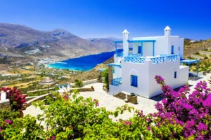 Luxury yacht sailing near Amorgos, Greece, with dramatic cliffs, whitewashed villages, and deep blue Aegean waters.