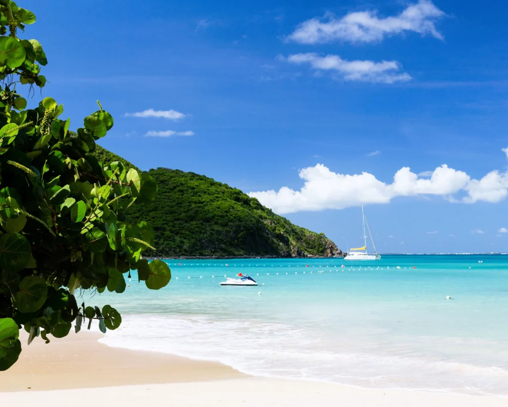 Luxury yacht anchored nearAnse de Marcel, St. Martin, with calm turquoise waters, lush green hills, and a peaceful beach cove.