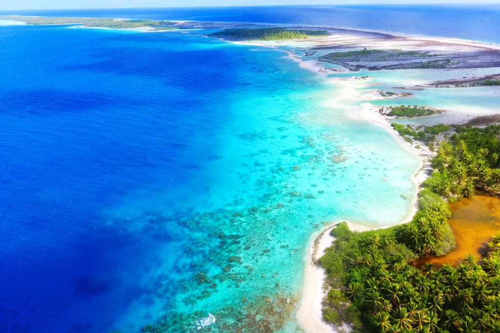 Luxury yacht anchored near Apataki Atoll, Tuamotus, French Polynesia, surrounded by turquoise lagoon waters, coral reefs, and palm-fringed motus.